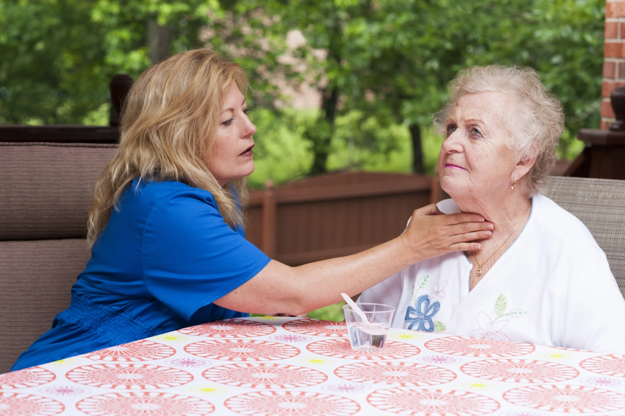 Caregiver checking elderly woman's throat.