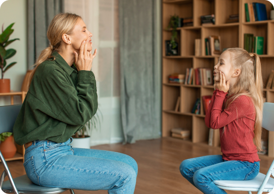 Woman and girl touching faces, sitting.